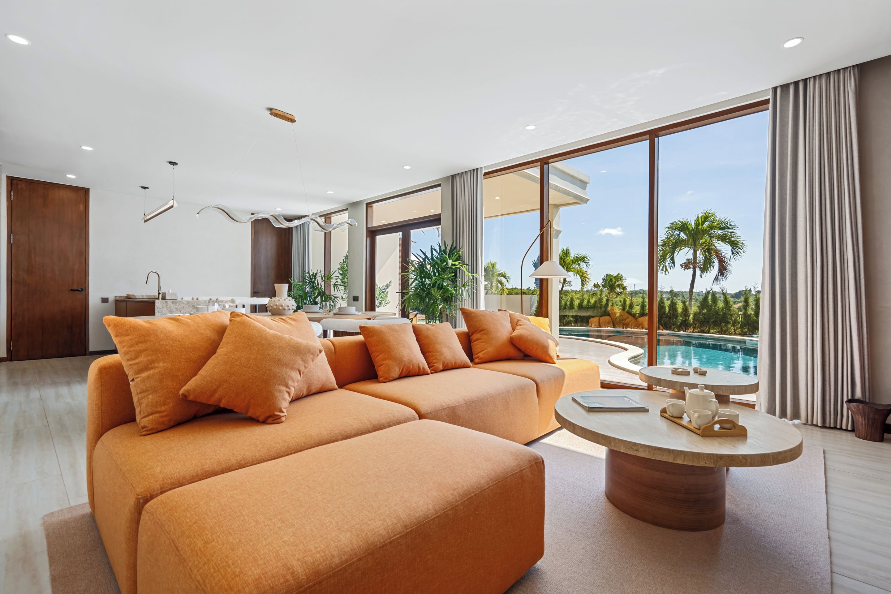 A modern living room with a sectional sofa, a coffee table, and a view of a swimming pool.