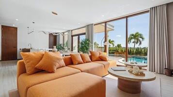 A modern living room with a sectional sofa, a coffee table, and a view of a swimming pool.