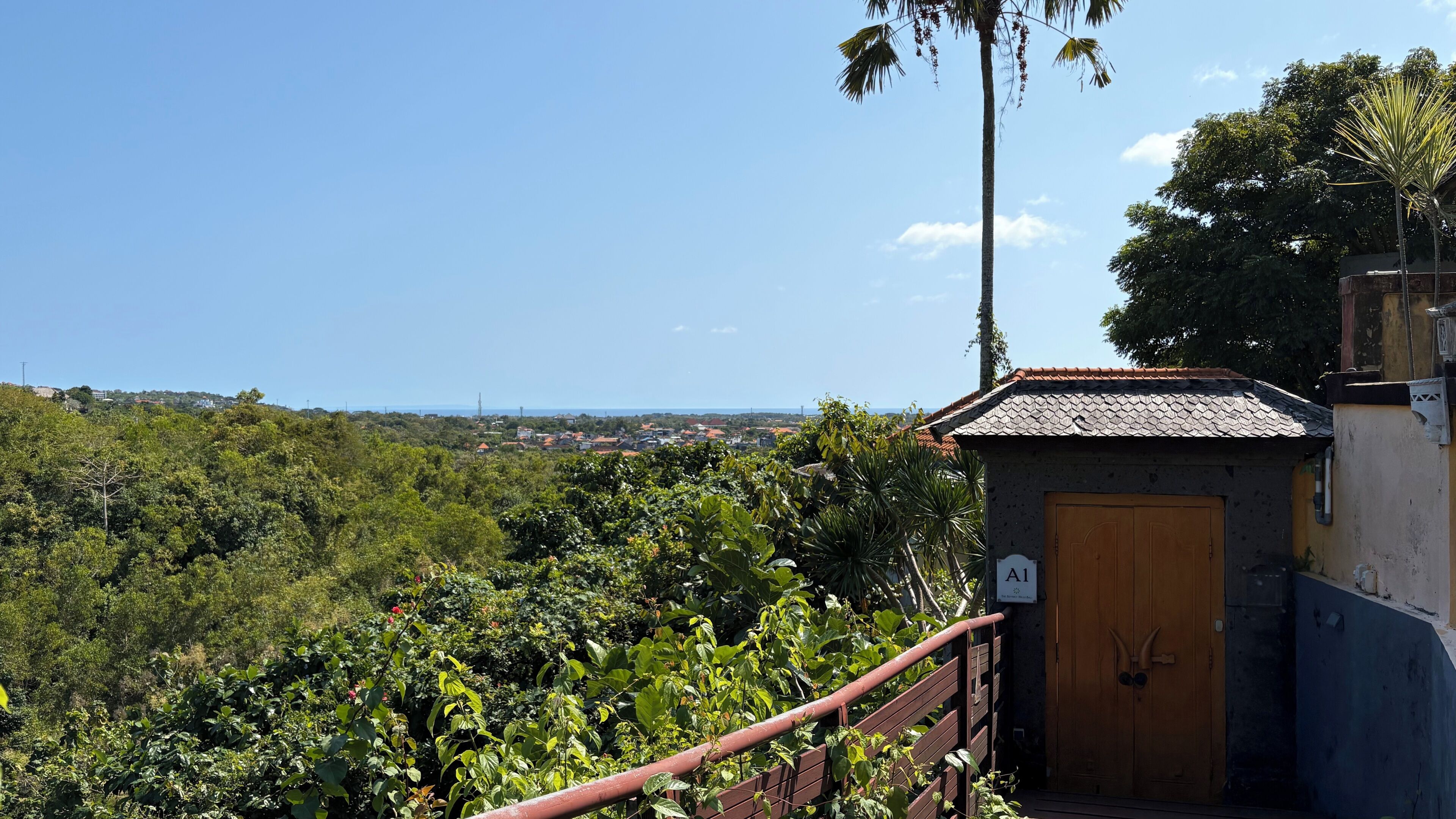 A view of a lush green landscape with a small building featuring a wooden door and a sign labeled 'A1'.