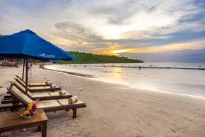 Vlak bij het strand, wit zand, ligstoelen, parasols