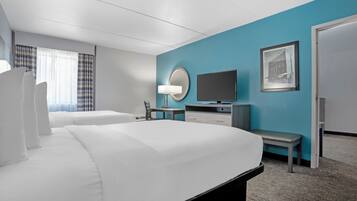 Een hotelkamer met een groot bed, een bureau, een stoel, een televisie, een lamp en een ingelijst schilderij aan de muur.