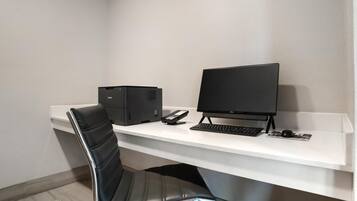 Un espacio de oficina moderno con un escritorio blanco, una silla de oficina negra, un ordenador de sobremesa e impresora.