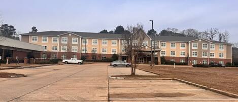 A multi-story building with a parking lot in front.