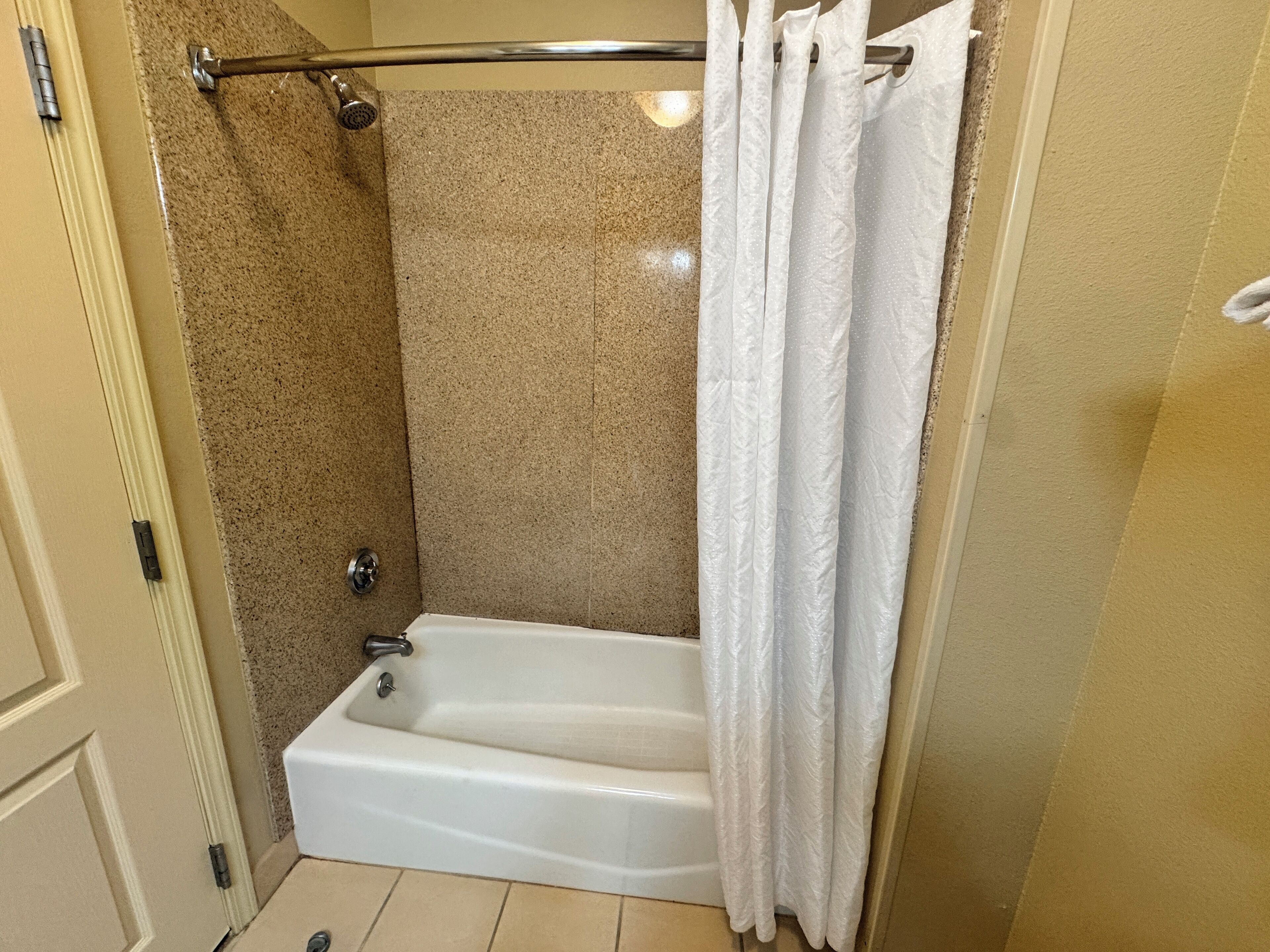 A shower area with a bathtub, a shower curtain, and a towel rack.