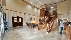 A spacious lobby with a tiled floor, a staircase, and a Christmas tree. - Hotel Pineville & Conference Center Alexandria I-49 (Pineville)