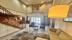 A spacious lobby with a staircase, a large sofa, two armchairs, a Christmas tree, and a chandelier. - Hotel Pineville & Conference Center Alexandria I-49 (Pineville)