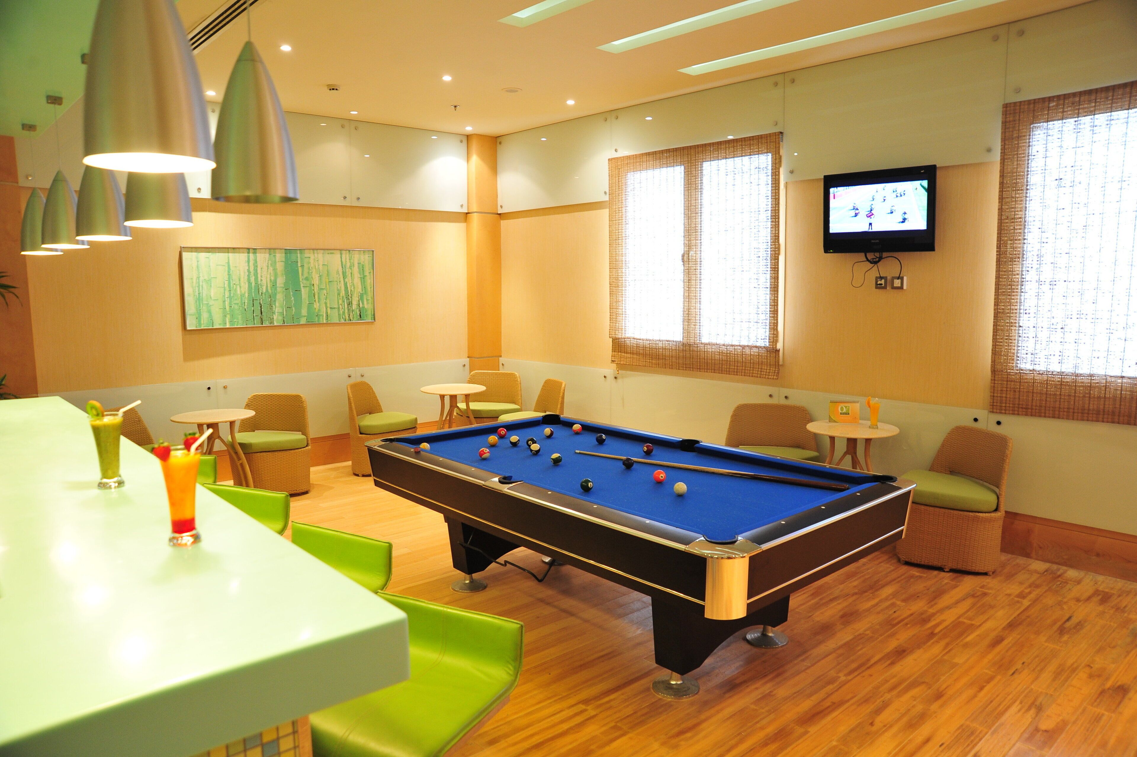 Una mesa de billar en una habitación con televisión, sillas y una mesa con bebidas.