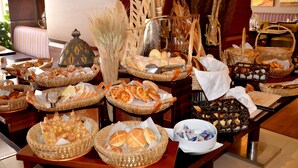 Una mesa de bufé con diversos panes, pasteles y una decoración central.