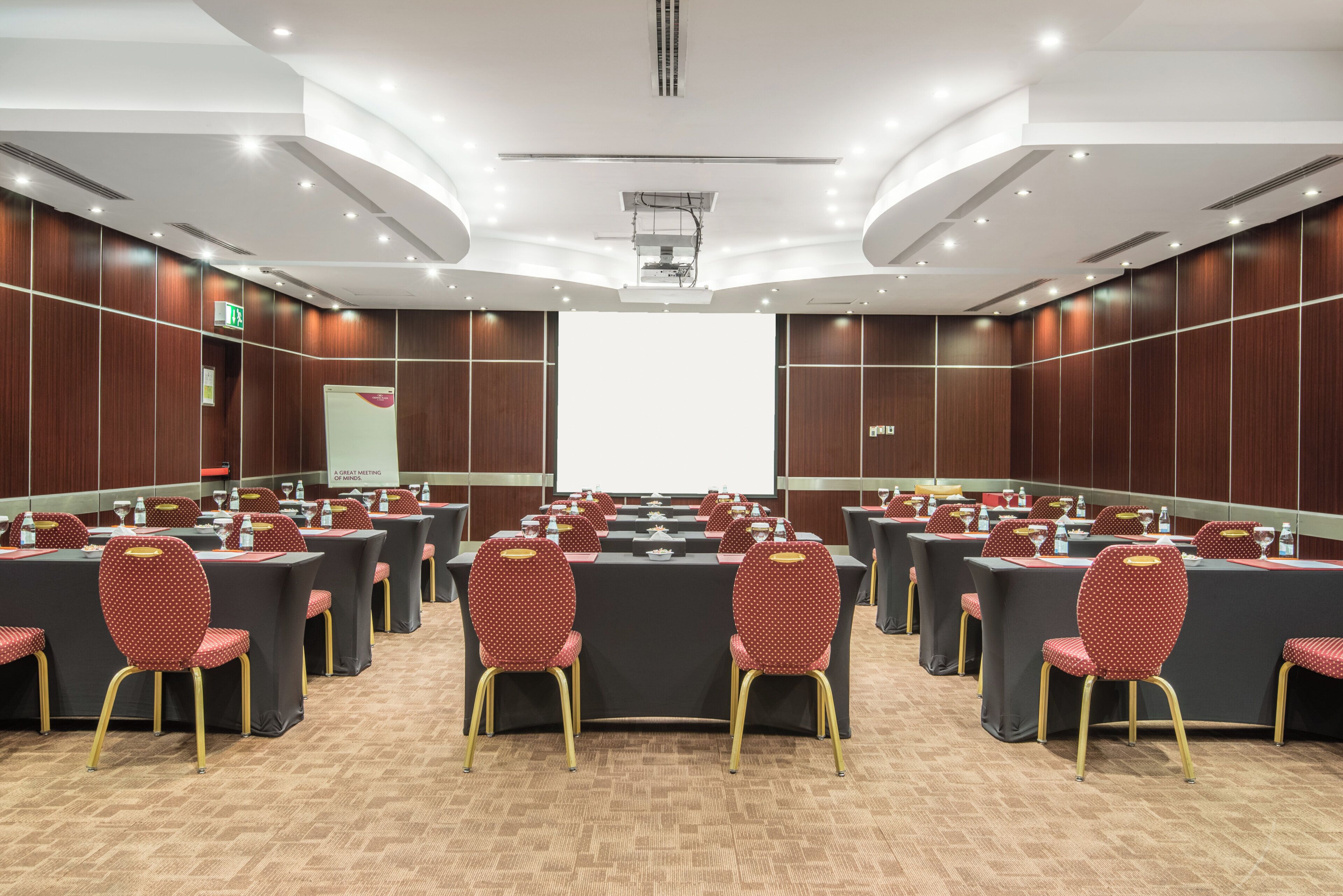 Une salle de conférence équipée d’une longue table, de nombreuses chaises et d’un écran de projection.