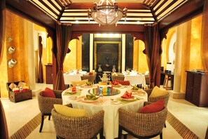A formal dining room with round tables, wicker chairs, and a chandelier. - Crowne Plaza Al Khobar by IHG (Al Khobar)