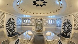 Un cuarto de spa con una camilla de masaje central, dos sillas de masajista y un techo decorado con motivos de estrellas.