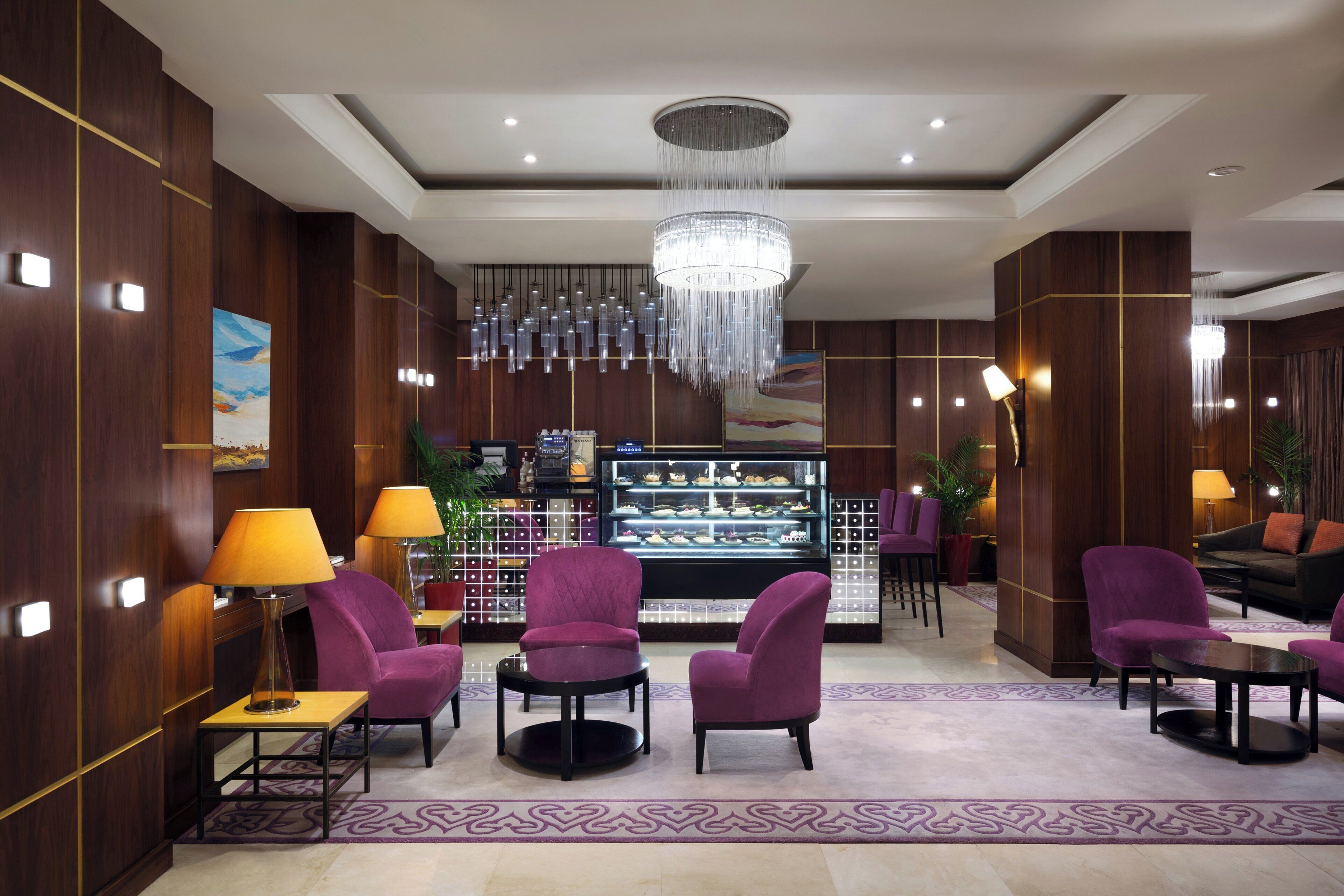 A lobby with purple seating, a chandelier, and a display case with items.