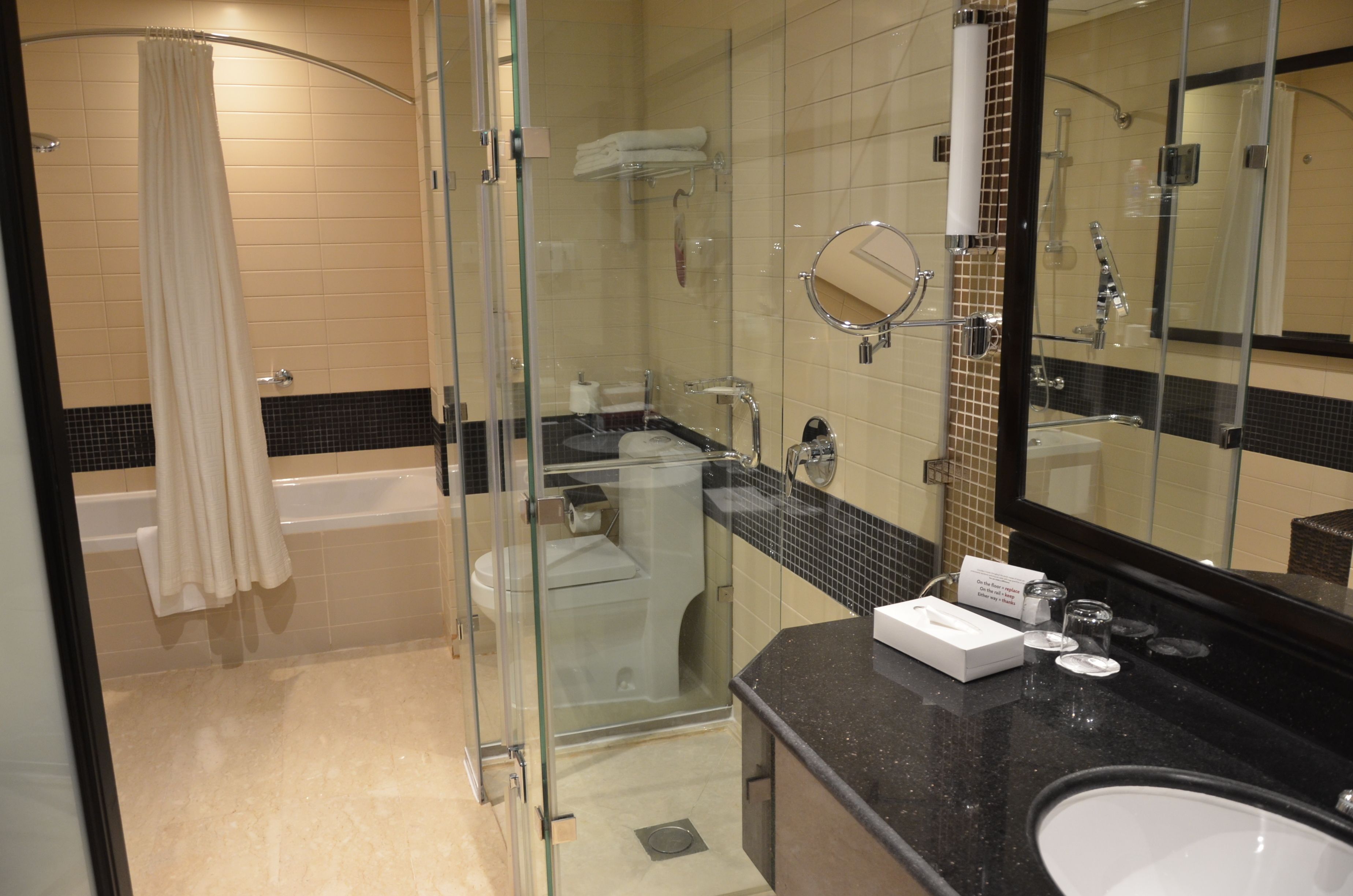 A modern bathroom with a glass-enclosed shower, a bathtub, a vanity with a mirror, and a toilet.