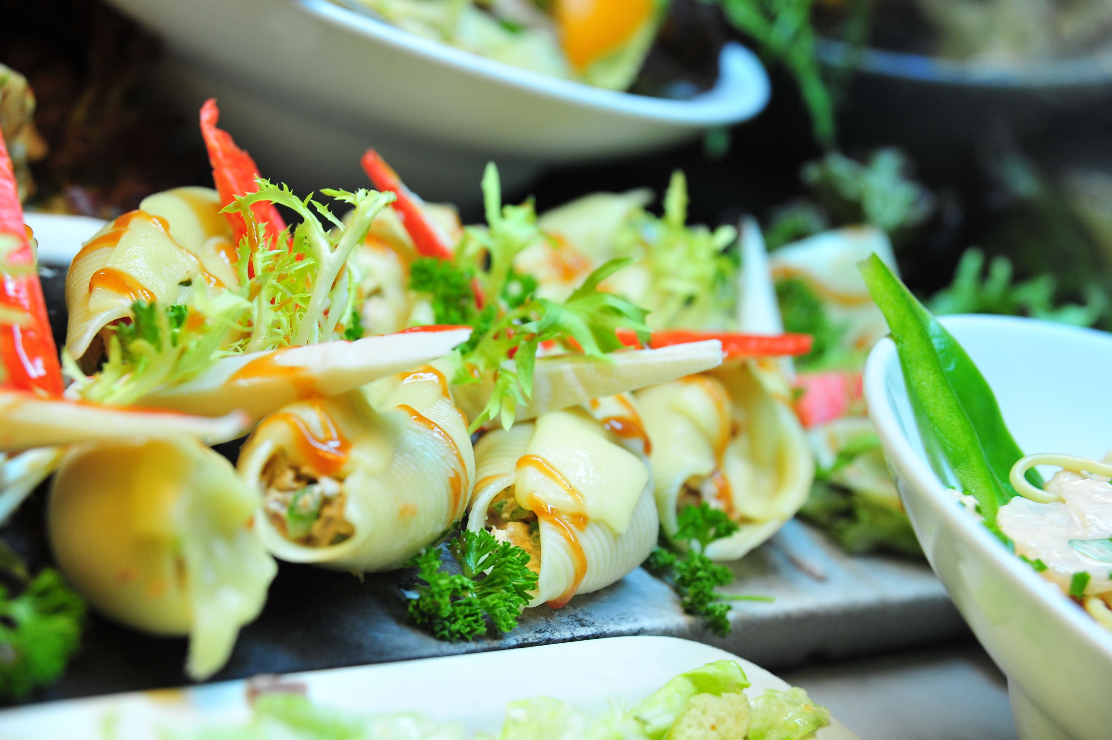 Diversos aperitivos, incluindo rolinhos com molho e guarnições, dispostos em um prato de servir.