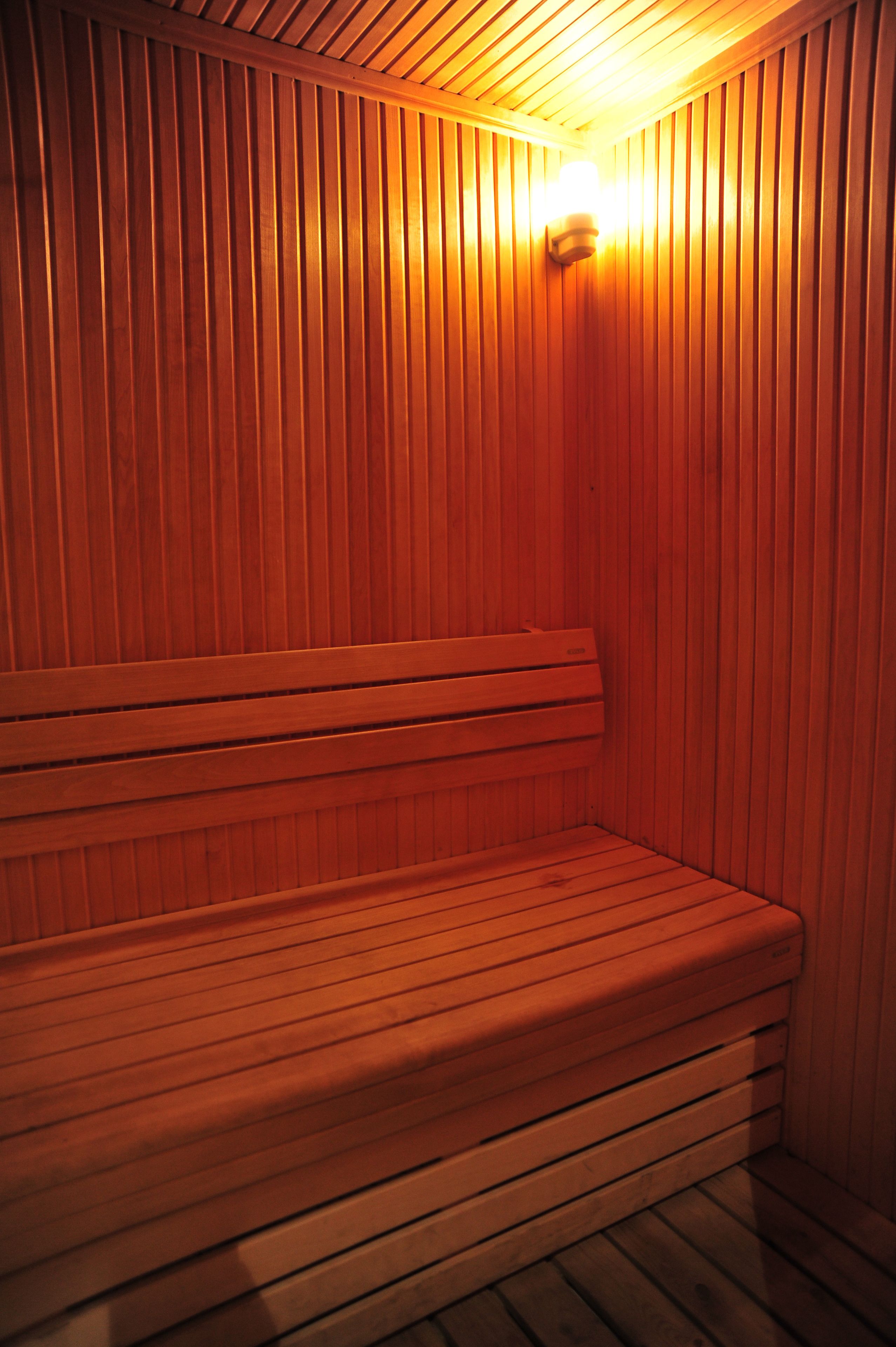 Una sauna de madera con un banco y una luz fijada en la pared.