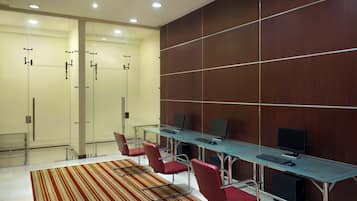 A conference room with glass partitions, a long table with computers, and red chairs.