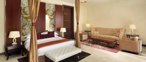 A hotel room with a four-poster bed, a sofa, two bedside tables with lamps, and a large mirror.