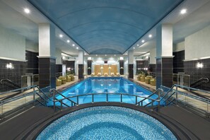 A large indoor swimming pool with a tiled floor, surrounded by lounge chairs and a sunroof ceiling. - Crowne Plaza Al Khobar by IHG (Al Khobar)