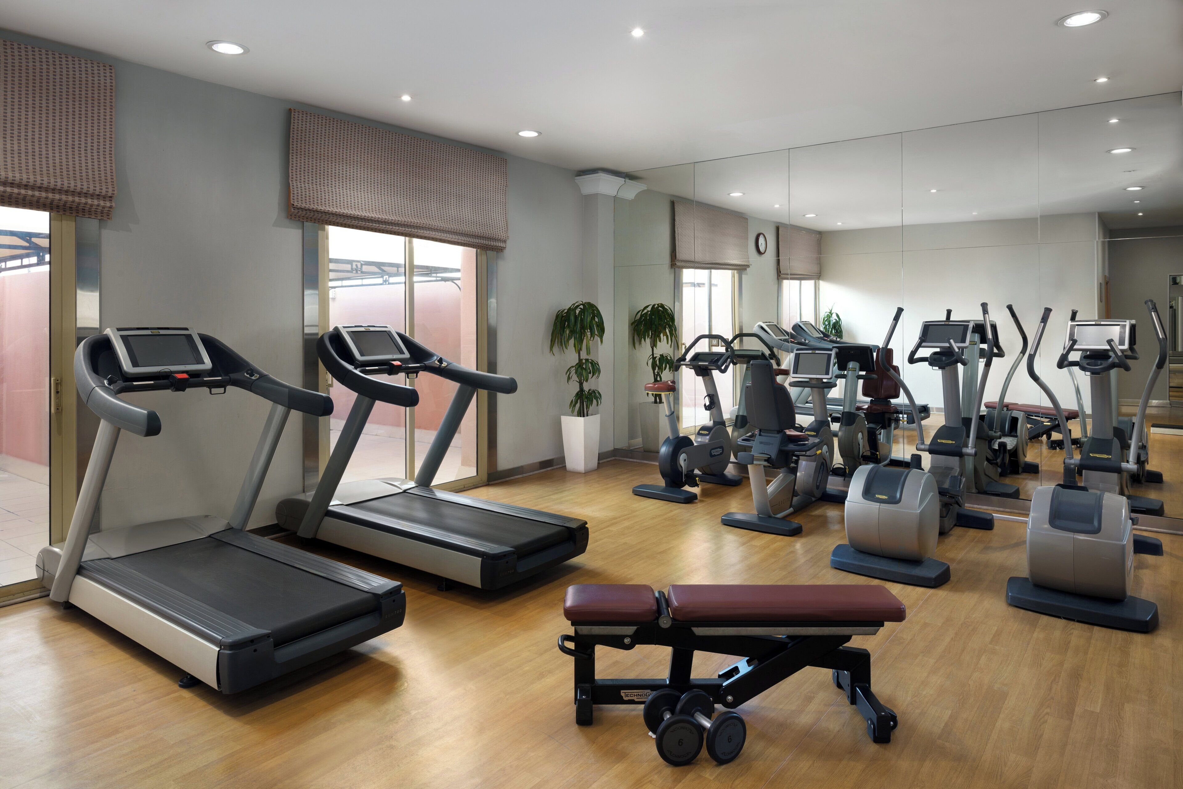 A gym with treadmills, elliptical machines, and a bench.