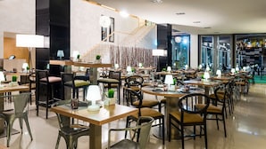 A modern restaurant with multiple dining tables and chairs, a staircase, and a view of the city through large windows. - Zentral Ave (Zaragoza)