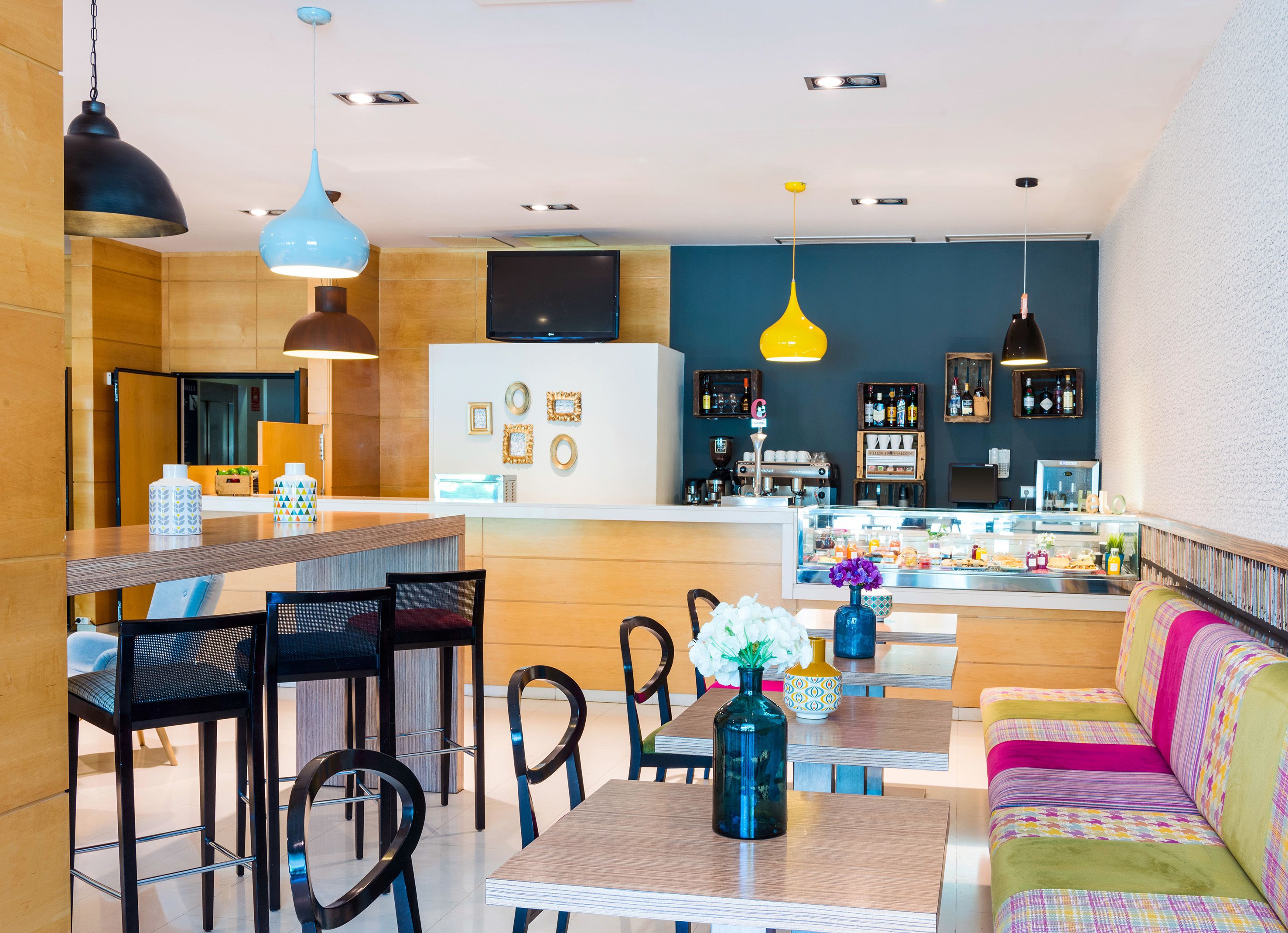 Un interior moderno con una zona de bar, asientos y una cocina al fondo.