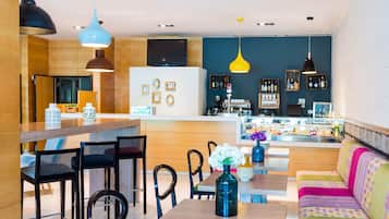 Un interior moderno con una zona de bar, asientos y una cocina al fondo.