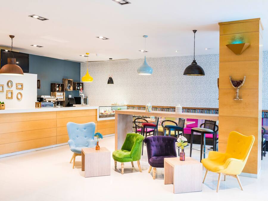 A modern interior with a reception desk, colorful chairs, and pendant lighting.