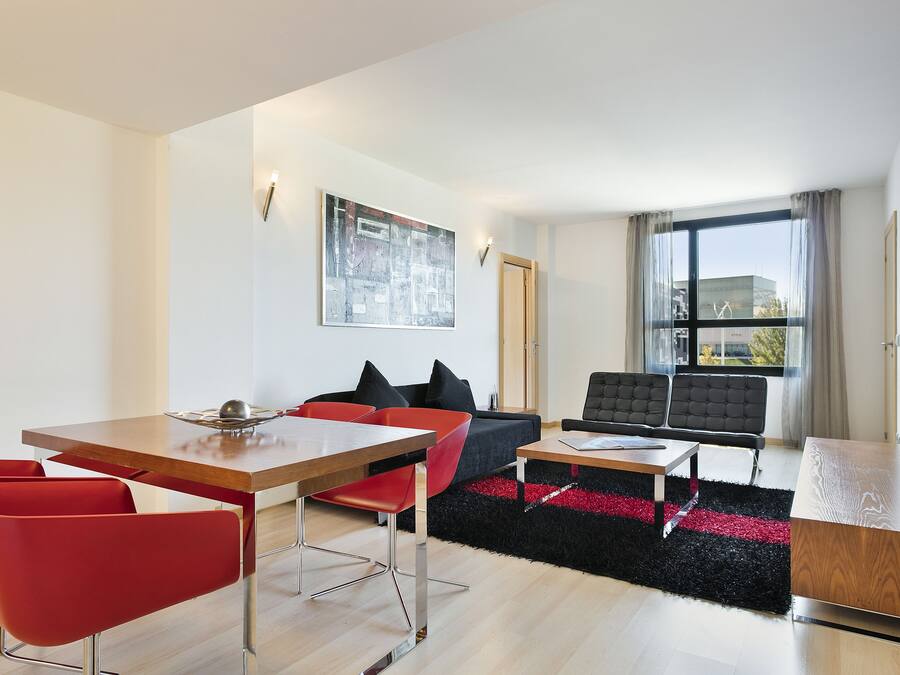 Una sala de estar moderna con comedor, que incluye un sofá, sillas, una mesa de centro y un televisor.