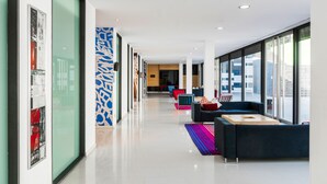 A modern hotel lobby with a long corridor, seating areas, and large windows. - Zentral Ave (Zaragoza)