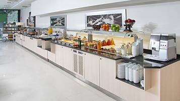 A buffet setup with various food items, a coffee machine, and a fruit bowl.