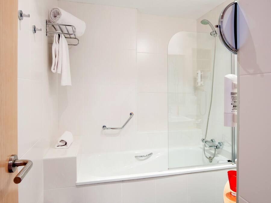 A modern bathroom with a glass-enclosed shower, a white bathtub, and a towel rack.