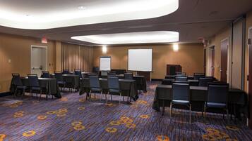 A conference room with tables and chairs, a whiteboard, and a carpeted floor.