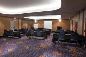 A conference room with tables and chairs, a whiteboard, and a carpeted floor.