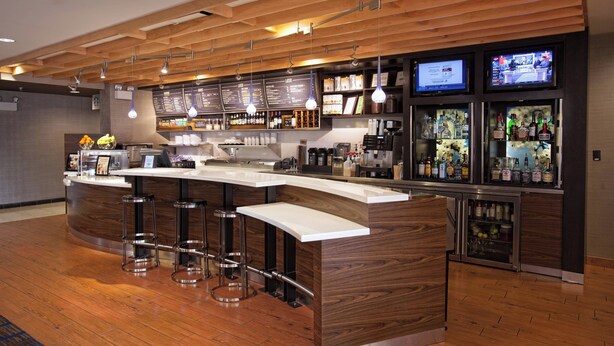 Zona de bar moderna con una barra curva, taburetes y un panel de menú.