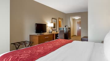 Una habitación de hotel con cama, escritorio con ordenador, televisión y espejo.