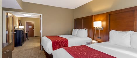 Une chambre d’hôtel avec deux lits, un bureau et un miroir.