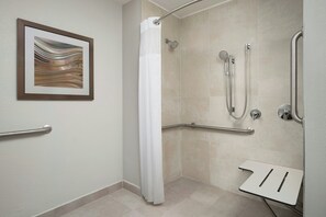 A modern bathroom with a shower, grab bars, and a framed artwork on the wall. - Courtyard by Marriott Fort Myers I-75/Gulf Coast Town Center (Fort Myers)
