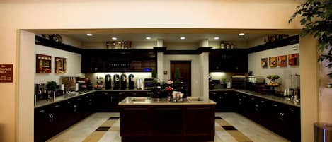 A spacious kitchen with a central island, dark cabinetry, and a patterned floor.