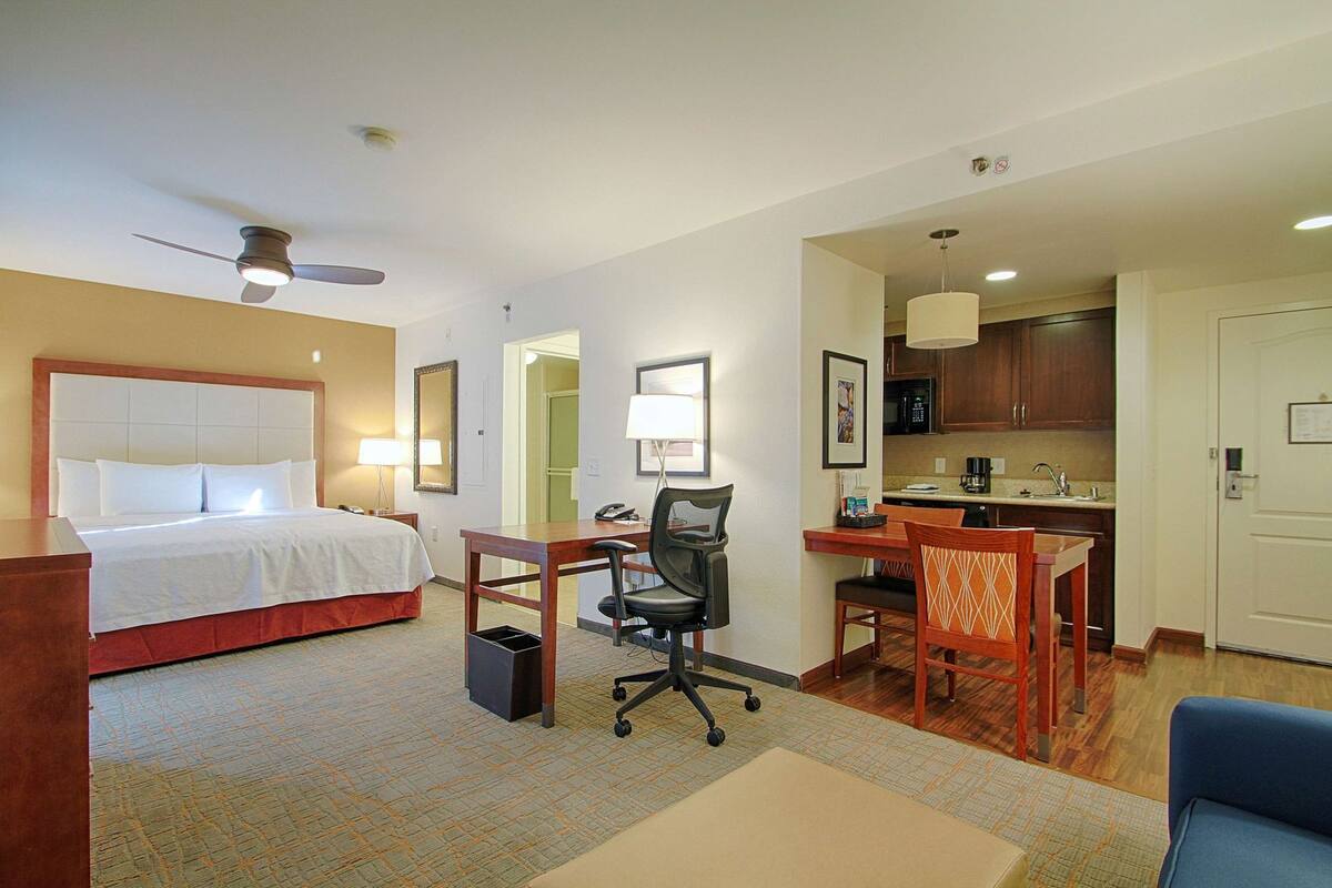 Une chambre d’hôtel comprenant un lit, un bureau, un fauteuil de bureau, une kitchenette et un coin repas.