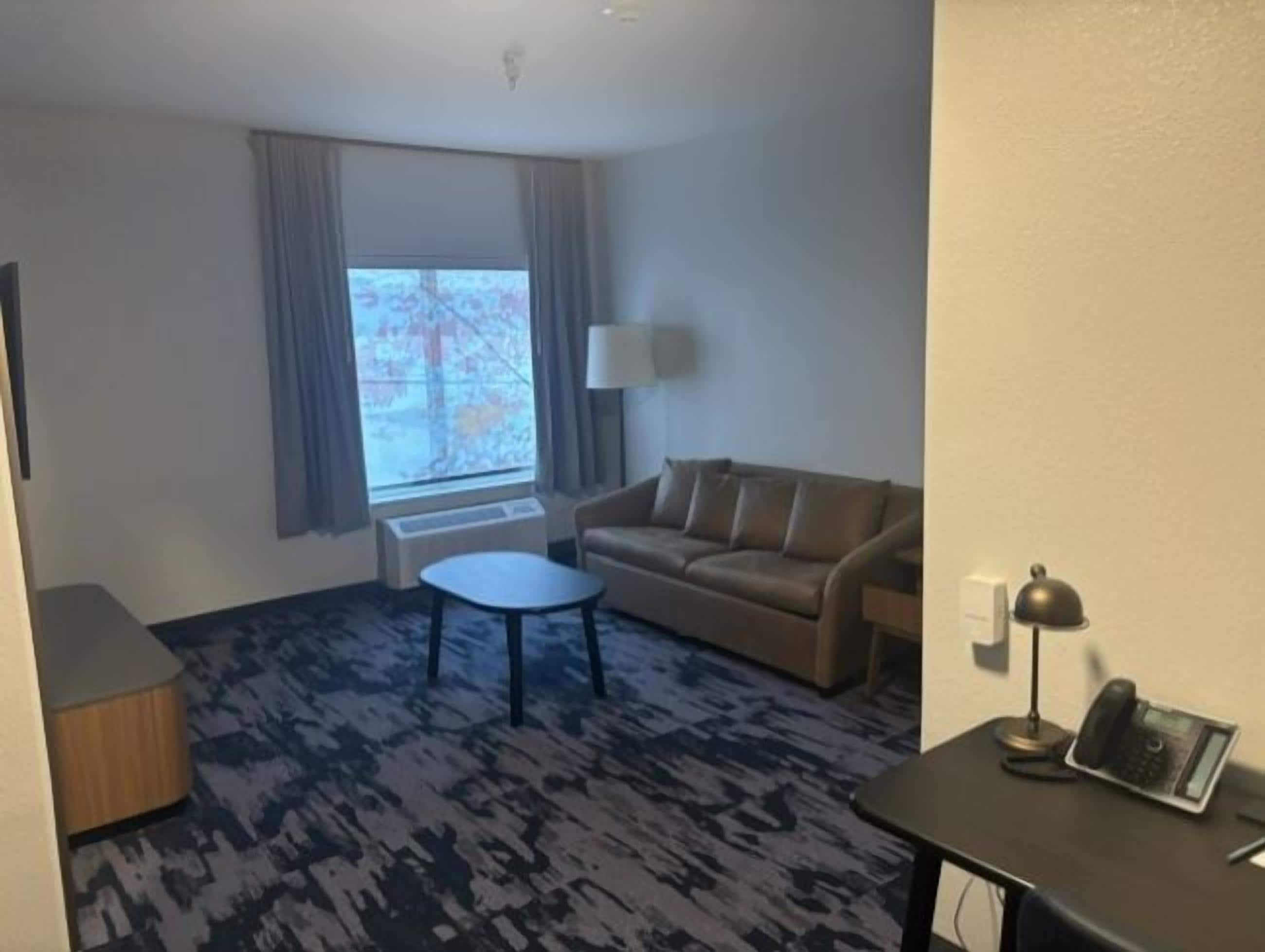 Une chambre d’hôtel avec un canapé, une petite table, une lampe et un téléphone.