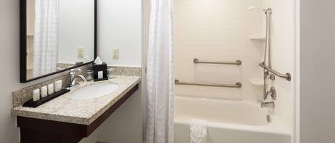 A bathroom with a sink, mirror, shower, and bathtub.