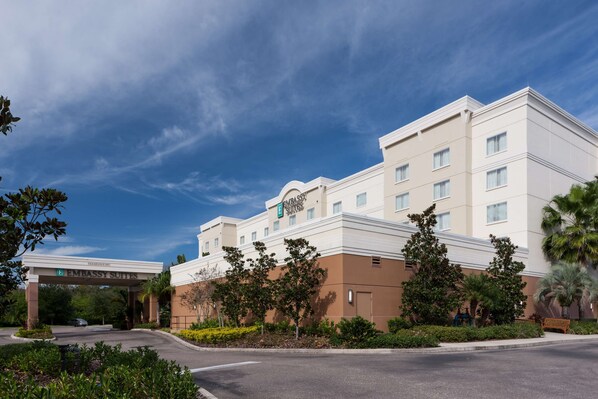 A multi-story hotel with a modern design, featuring a prominent entrance with a sign, landscaped surroundings, and a clear sky. - Embassy Suites by Hilton Tampa Brandon (Tampa)