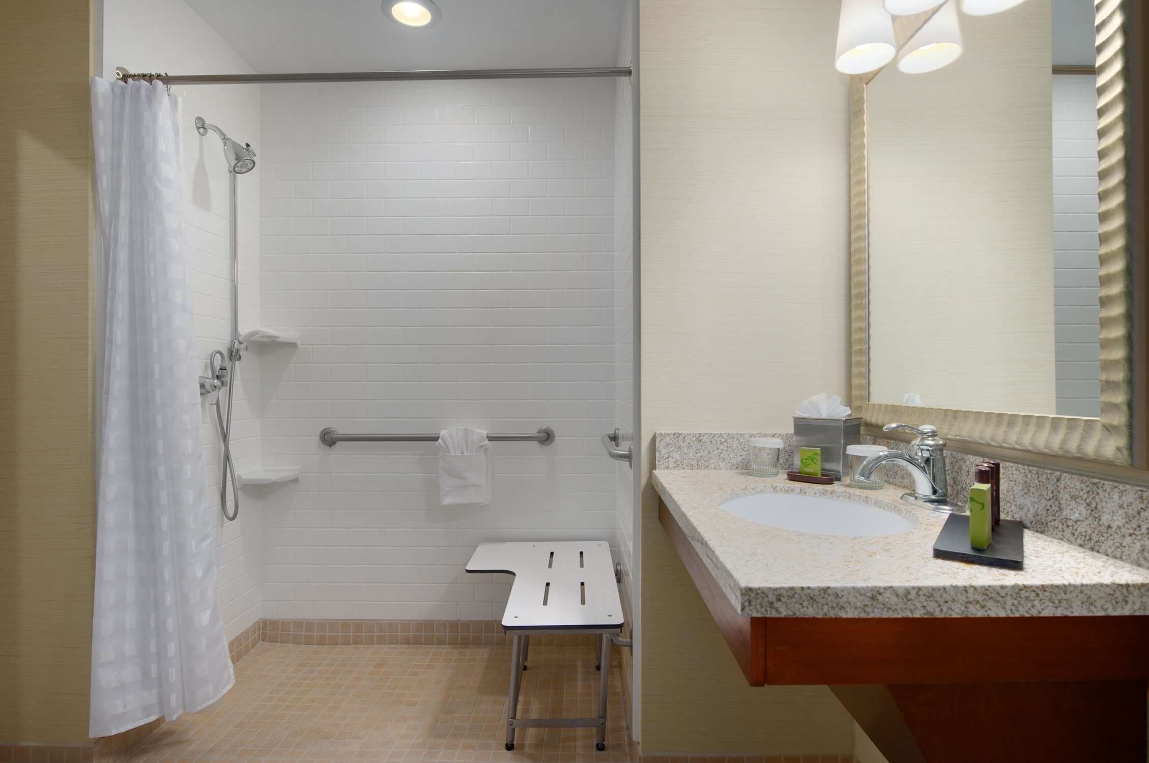 A bathroom with a shower, a sink, and a mirror.