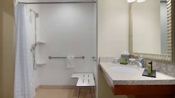 Un baño con ducha, lavamanos y espejo.