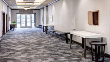 A hallway with a patterned carpet, a reception desk, a bench, and a door at the end.