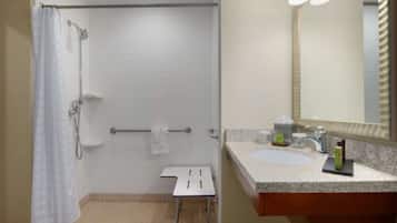 Un baño con ducha, lavabo, espejo y toallero.