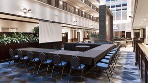 Una amplia sala de conferencias con una larga mesa y sillas, rodeada por un techo alto e iluminación moderna.