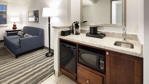 Un espacio habitable compacto con sofá, cafetera, microondas y pileta en un kitchenette.
