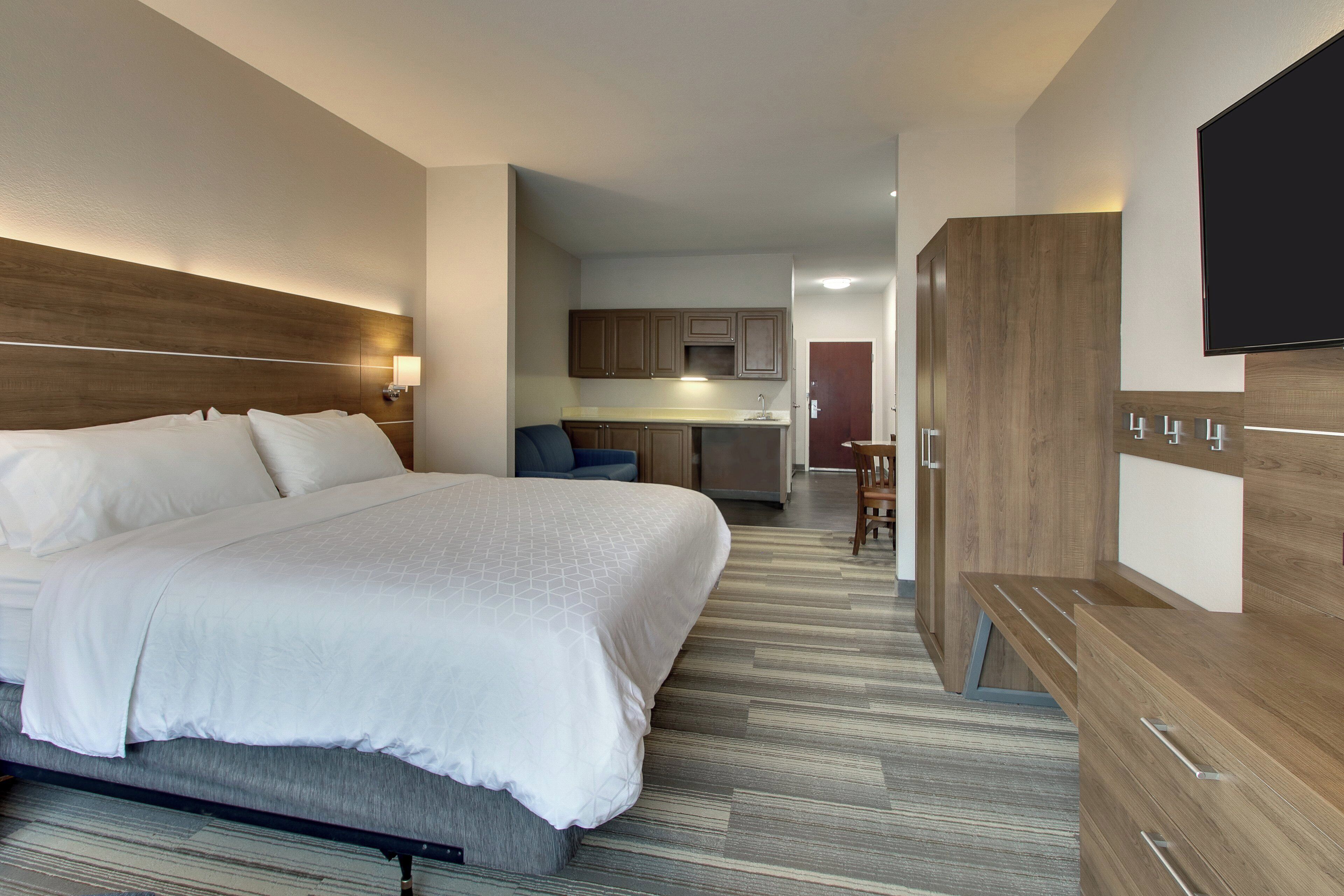 A hotel room with a bed, a desk, and a kitchenette.