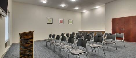 Konferenssitila, jossa on riveissä tuoleja, puhujapönttö ja seinillä tauluja.